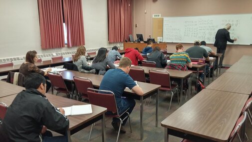 a medium sized classroom with a professor writing on the board