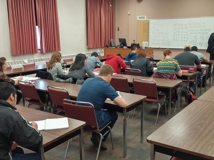 a medium sized classroom with a professor writing on the board