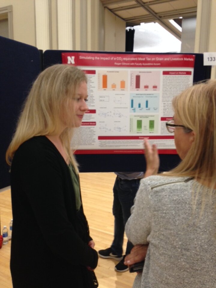 two individuals talking about a project in front of a poster board